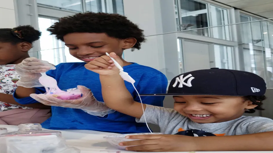 Two children stand alongside each other as they make slime solutions together during the Wellness Center's 'Slime Time' event for Manhattanville's Community Day in April 2019.
